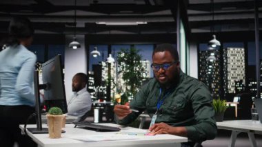 Erkek danışman aylık raporlar için el yazısı notları hazırlıyor, finans belgelerinden önemli ayrıntıları çıkarıyor ve iş hedefleri ve yaklaşan görevler için özet çıkarıyor. Kamera A.