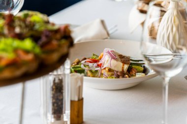 salad with cheese with fresh vegetables and olives with sauce on a plate on a served table