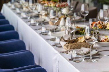 a large table with a tablecloth served with plates with cloth napkins with knives and glasses with food