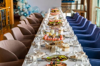 a large table with a tablecloth served with plates with cloth napkins with knives and glasses with food
