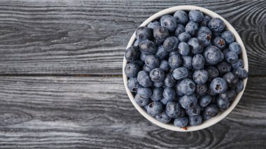 ripe blueberries on a wooden table in a plate, top view shot close-up, vitamins