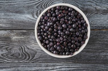 ripe whortleberry in a plate on the table, close-up view from the top