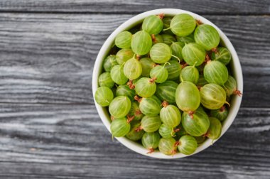 ripe agrus, gooseberries in a plate on the table, close-up top view