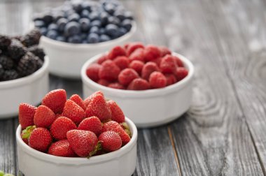 strawberries in a white bowl, blueberries, gooseberries, currants, shot close-up