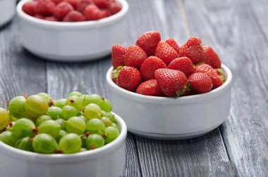 strawberries in a white bowl, blueberries, gooseberries, currants, shot close-up