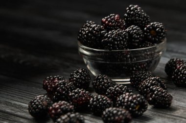 Blackberries on a dark background in bowls, ripe juicy berries on the table, close-up shot