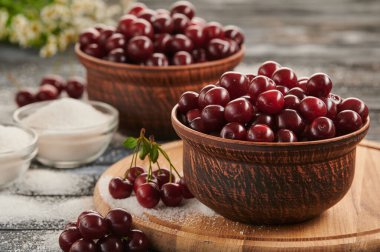 berries in bowls, ripe cherries on a wooden table in plates, sugar in a saucer