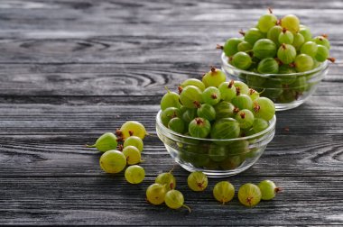 ripe gooseberries on a wooden table in glass plates, berries in glass saucers