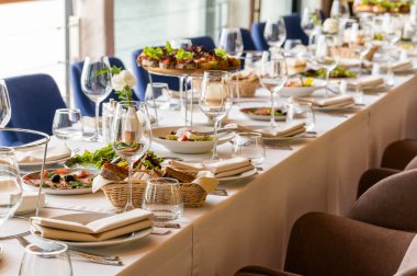 a large table with a tablecloth served with plates with cloth napkins with knives and glasses with food