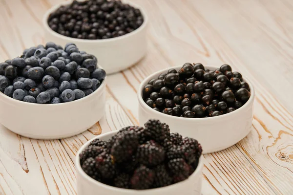 ripe blueberries, wild berries in bowls, among the assortment of ripe berries, raspberries, blueberries, gooseberries, currants, close-up shot