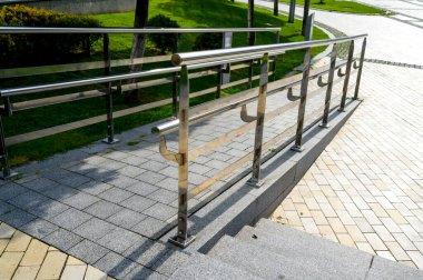 Mimarinin peyzaj tasarımında krom parmaklıklardan yapılmış granit ve mermerden yapılmış yürüyüş yolu.
