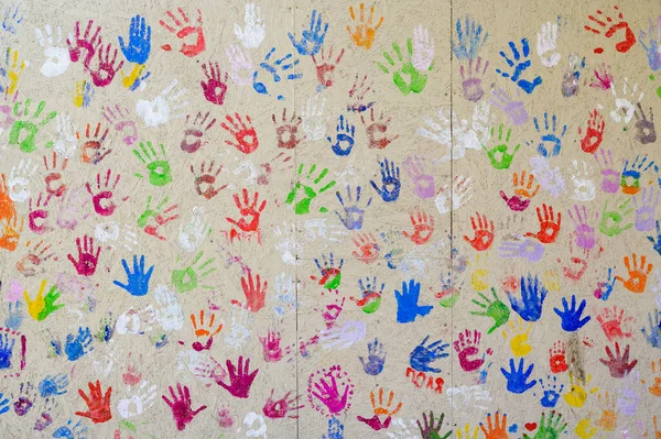 prints of children\'s hands in multi-colored paint on the wall, colored prints of the palms, close-up shot