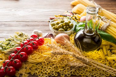 Unlu yumurta, taze domates, dilimlenmiş mantar ve zeytinyağının yanında farklı türde çiğ makarna.