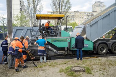 Bir grup yol işçisi ellerinde kürek ve kaldırım onarımı ile yolun bir kısmını asfalt ve yol inşaatı ile dolduruyorlar.
