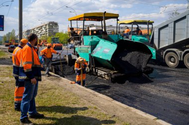 Bir grup yol işçisi ellerinde kürek ve kaldırım onarımı ile yolun bir kısmını asfalt ve yol inşaatı ile dolduruyorlar.