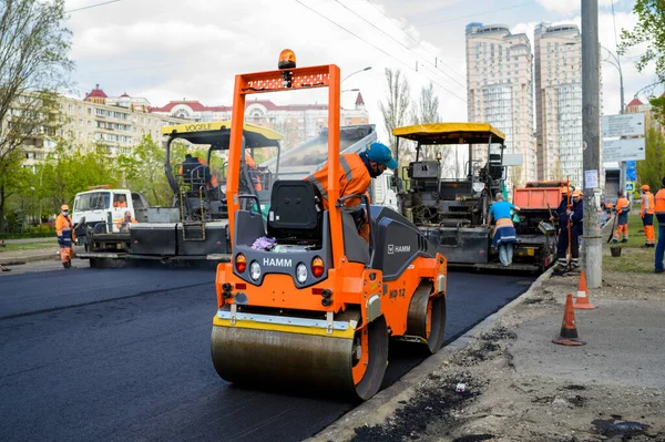 使用铲子和铺路工的一组道路工人用新鲜沥青修路 图库图片