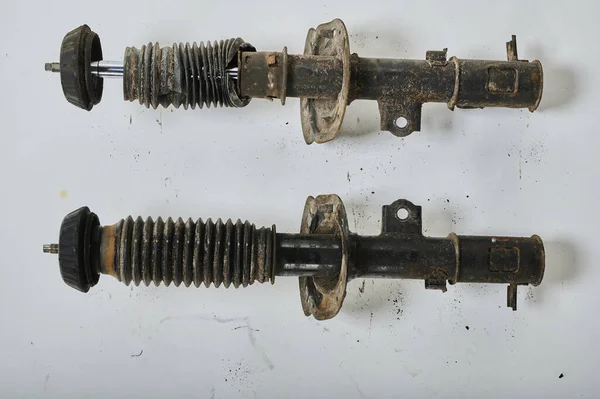 Eski şok emici destekleri arabadan sökülmüş, kullanılmış parçalar, homojen bir arka plana doğru çekilmiş.