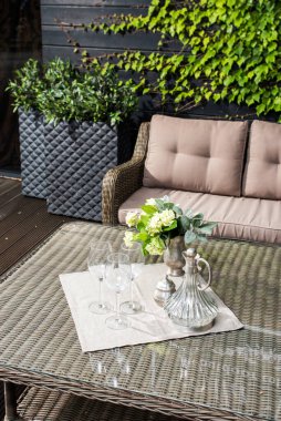 Yemek masasında cam eşyalar kumaş peçetede dış mobilyalar yeşil arka planda.