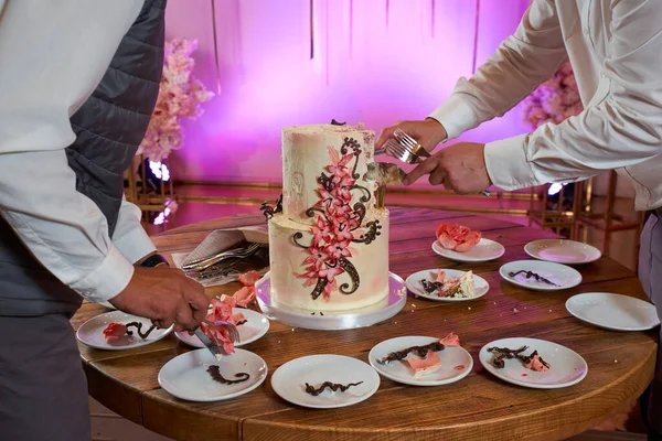 the process of cutting and serving a birthday cake decorated with artificial flowers and chocolate
