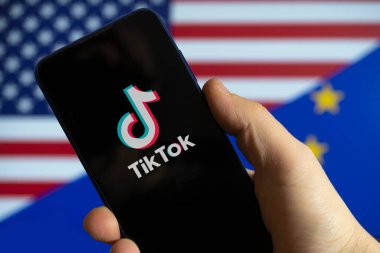 Carrara, Italy - February 28, 2023 - The TikTok logo with the US and EU flags in the background