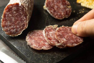 Adam taze İtalyan salamından bir dilim alıyor.