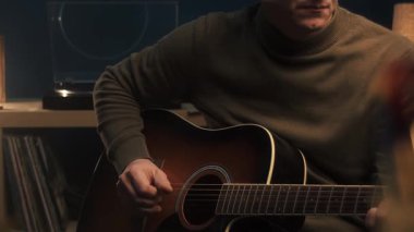 Adam akustik gitarla arpeggio çalıyor.