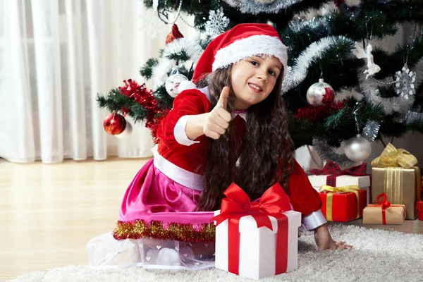 家で装飾されたクリスマスツリーの近くに座っている箱の中の贈り物とサンタの服を着た幸せな女の子 クリスマス 冬の休日や家族の概念のお祝い — ストック写真