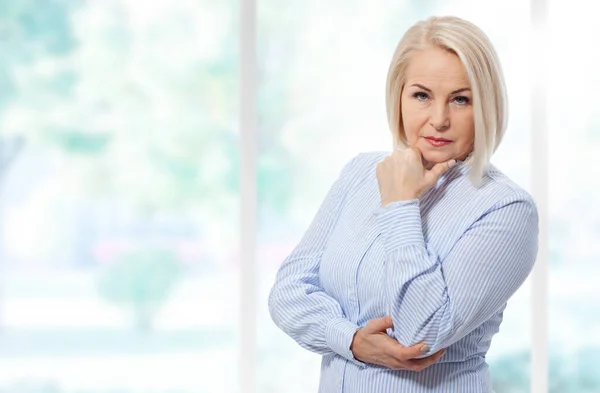 窓の近くに立って青いシャツに折り畳まれた腕を持つ深刻なビジネス女性 選択的焦点 — ストック写真