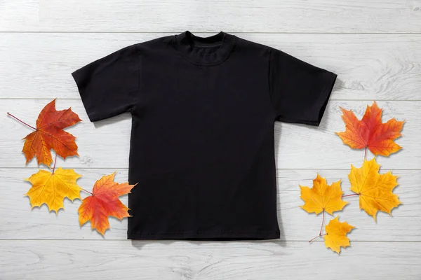 白い木の背景に黒いTシャツの小さな男の子のフロントビュー デザインクローズアップのためのモックアップ — ストック写真