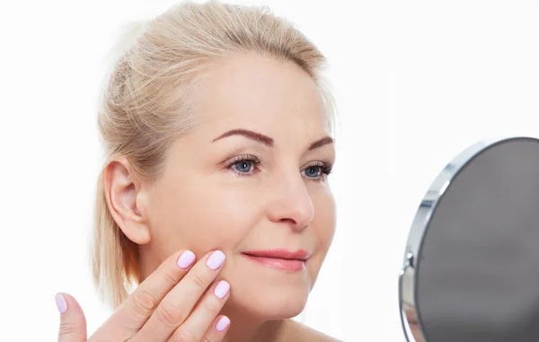 快乐的中年女性模特儿摸着镜子里的脸皮 笑成熟的老太太享受健康的皮肤护理 美容美发 护肤处理化妆品概念 — 图库照片