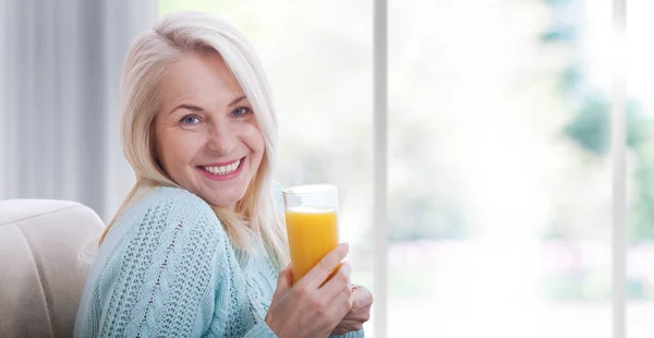 Woman Holds Glass Orange Juice Looks Relaxed Camera Sitting Window — Stock Photo, Image