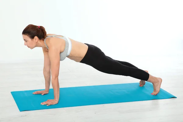 stock image Full-length distance photo amazing fit adult woman doing exercise on yoga mat in fitness studio. Concept people are workout in yoga, training in sports clothes isolated