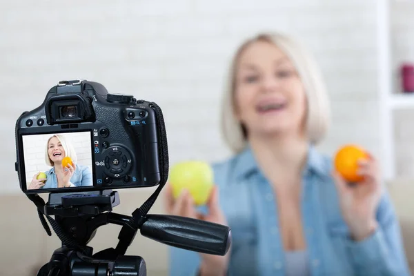 Fröhliche Bloggerin Zeigt Hause Früchte Vor Der Kamera lizenzfreie Stockbilder