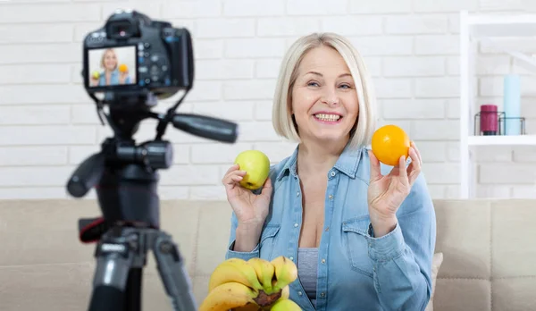 즐거운 블로거는 집에서 카메라에 과일을 보여줍니다 스톡 사진