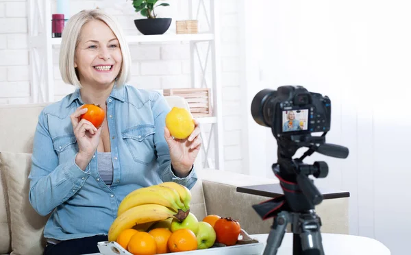 快乐的女性专家营养师在工作室里向摄像机展示水果 图库图片