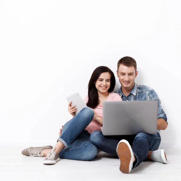幸福的年轻夫妇坐在地板上 带着笔记本电脑寻找他们的新家和家具 模拟设计 免版税图库图片