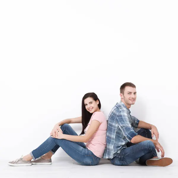 幸福的年轻夫妇坐在地板上抬头看着 同时梦想着他们的新家和家具 模拟设计 图库图片
