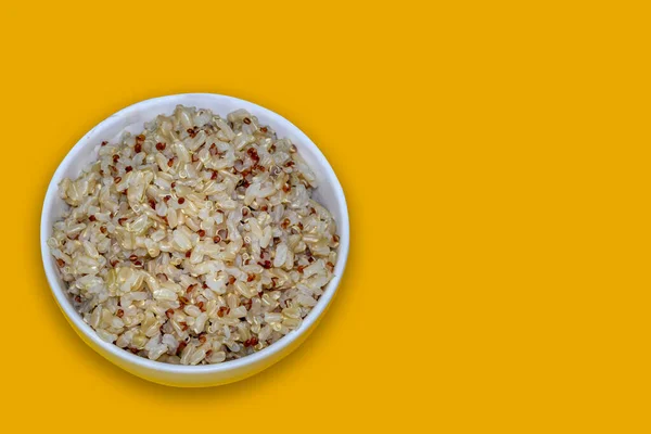 rice and quinoa in a bowl on yellow background with space for text . top view