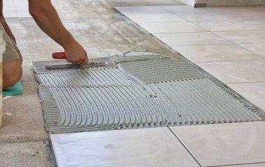 Bir evin zeminini döşeyen genç bir erkek işçi.