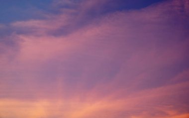 Günbatımı gökyüzü sıcak altın, mavi ve pembe renklerle parlar.