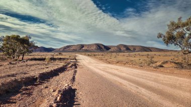 Dramatik, kurak bir arazi dramatik bulutlu bir gökyüzünün altında uzanıyor, uzak Gama Dağları 'na uzanan engebeli toprak bir yol izolasyon ve doğal güzelliği çağrıştırıyor..