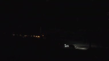 A tram filled with passengers pulls up to a stop in total darkness.
