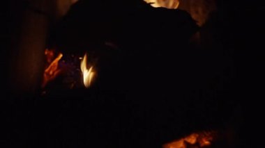 Stirring firewood to keep the fire and heat in the house, in a rustic old stove