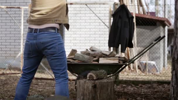 年轻人在他乡下的房子附近用一把锯子砍柴 — 图库视频影像