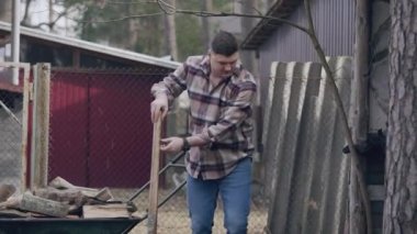 Two guys are working on site, one of whom is chopping logs, and the other is sawing a fallen tree branch.