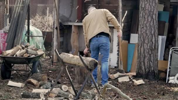 村里的一个人在他乡下的房子和外屋附近砍柴 — 图库视频影像