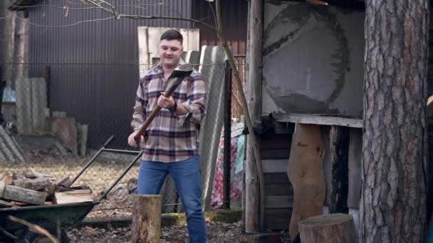 一个穿着格子呢衬衫和蓝色牛仔裤的男人正在用一把锯子劈柴 — 图库视频影像