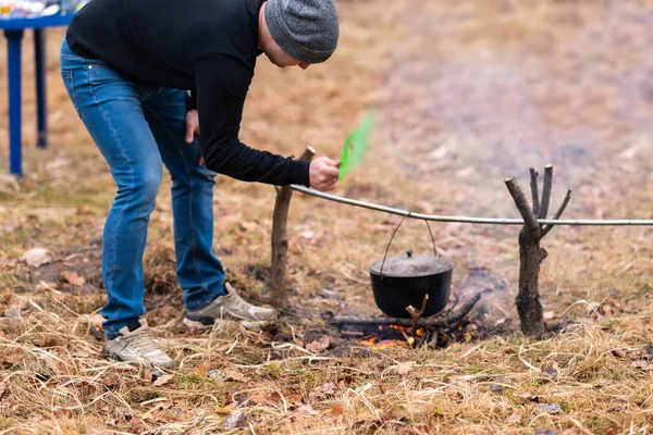 While camping in the forest, a guy cooks food on a fire