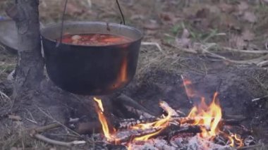 An open cast-iron cauldron with cooked food set aside from the hearth.