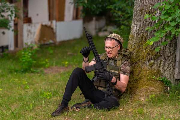 Soldato Stanco Sudato Controlla Sua Arma Mentre Seduto Sotto Albero — Foto Stock